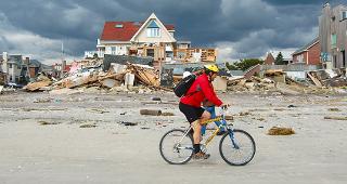 Man biking past homes destroyed by Superstorm Sandy © Paul Lurrie/Shutterstock.com
