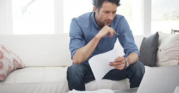 What documents are required for a personal loan? Man going over paperwork at home in living room | iStock.com/shapecharge