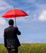 Man in field with red umbrella