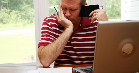 Boost your mortgage payments and save Man looking at his finances, holding wallet | iStock.com