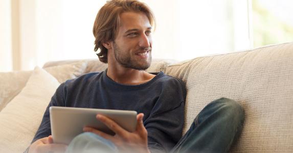Use your tax refund to shore up your finances Man relaxing with a tablet on the couch | CaiaImage/Getty Images