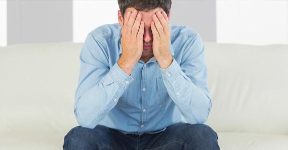 Stressed man sitting with head in his hands © iStock