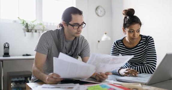 10 key tax terms to know Man and woman reading documents and browsing on laptop | Hero Images/Getty Images