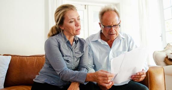 Figuring gain on rental property with 2nd mortgage A couple looking at papers in their living room | Simon Potter/Cultura/Getty Images