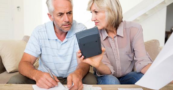 Mature couple computing budget in living room © iStock