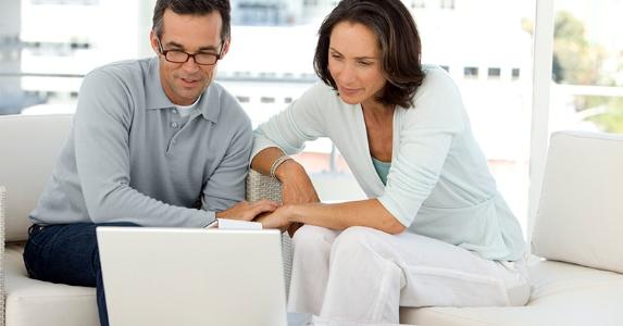 Mature couple reviewing finances on computer living room © iStock