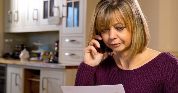 Woman on phone going over her bills © iStock