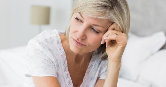 Woman seated on couch, thinking © iStock