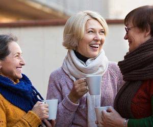 Mature women wearing sweaters, talking and drinking coffee © Iakov Filimonov/Shutterstock.com