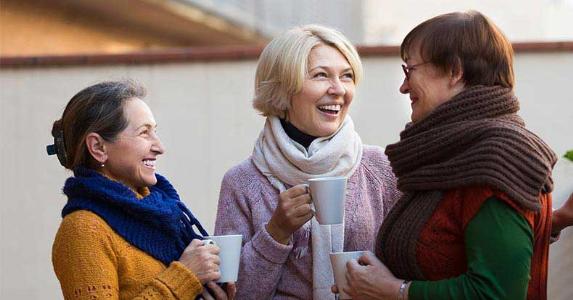 Mature women wearing sweaters, talking and drinking coffee © Iakov Filimonov/Shutterstock.com