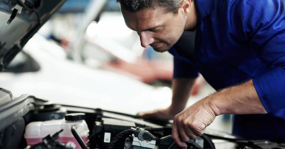 Adopt normal or 'severe' car maintenance schedule? Mechanic working under hood of car | iStock.com/kupicoo