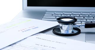 Medical bills, stethoscope on laptop © Gordon Swanson/Shutterstock.com