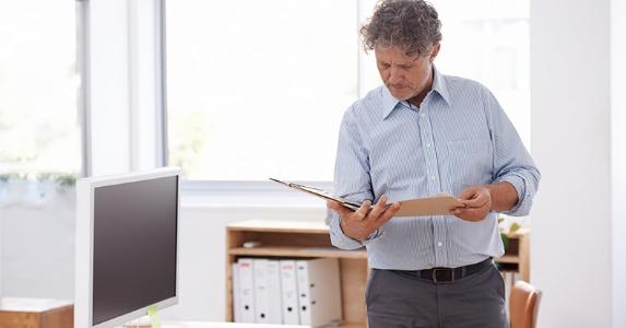 Fitting annuities into a retirement plan Middle aged man reading paperwork in office © iStock