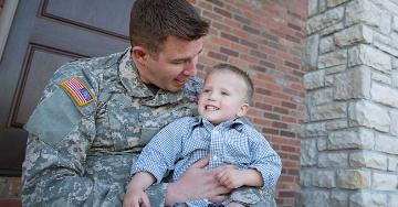 Military father holding his son on lap | Veterans United