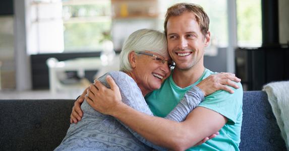 Mother hugging her son on the couch © iStock