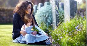 Mother holding child in cemetery © Yuri Arcurs/Shutterstock.com