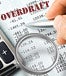 A magnifying glass over an overdraft statment and calculator