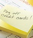 Hand pulling off Post-It note that says "Pay off credit cards!"