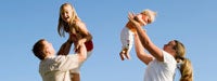 A man and woman holding a toddler and a baby up the air