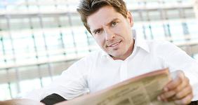 Man reading financial newspaper © MJTH/Shutterstock.com
