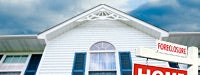 A shot of a white house with blue shutters, angled upwards and with a red foreclosure sign