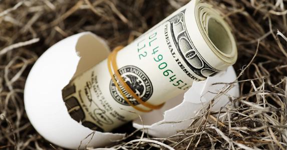 Should I raid my 401(k) to pay off the mortgage? Roll of $100 bills from cracked egg | iStock.com/bluestocking