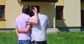 Same sex couple embracing in front of house © Karina Kononenko/Shutterstock.com
