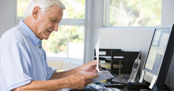Senior at desk looking over paperwork © Monkey Business Images/Shutterstock.com