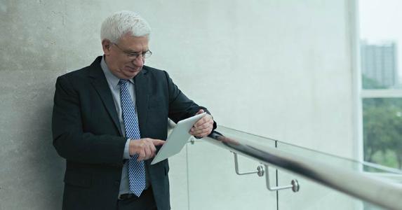 Hello Medicare, goodbye health savings account? Senior businessman browing on mobile table in office balcony © iStock
