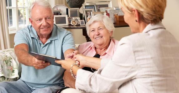 Try smaller banks for reverse mortgages Senior couple handing over signed papers in a folder to agent | iStock.com/Mark Bowden