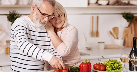The ins and outs of a reverse mortgage loan: Is it right for you? Senior couple hugging in kitchen | Dmytro Zinkevych/Shutterstock.com