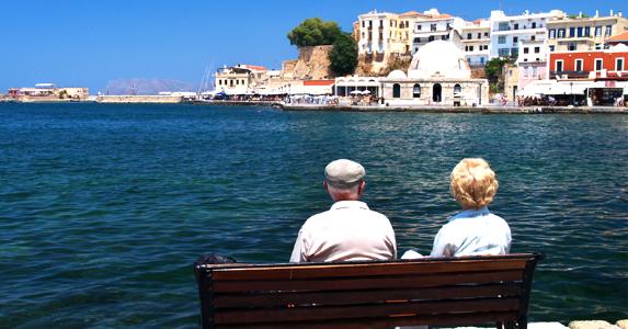 Senior couple sitting on a bench in overseas country © iStock