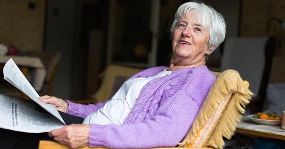 House-rich senior denied credit for home repairs Senior woman reclining and reading newspaper | iStock.com/ViktorCap