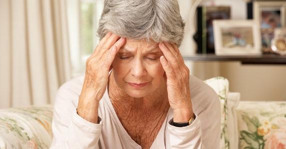Senior woman sitting on couch, sad © iStock