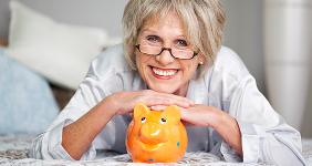 Happy senior woman posing with orange piggy bank © racorn/Shutterstock.com