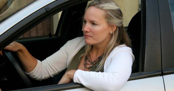 How to keep your car during bankruptcy Serious woman on white sweater sitting on driver's seat | iStock.com/LuisPortugal