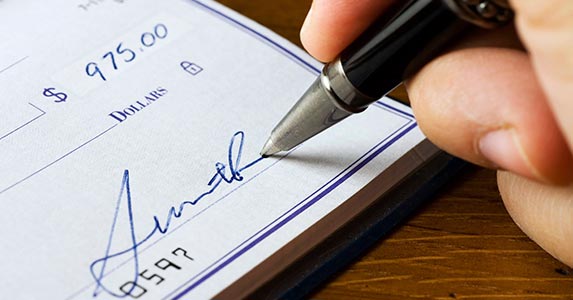 Signing someone else's name on a check Signing someone else's name on a check | bluestocking/E+/Getty Images