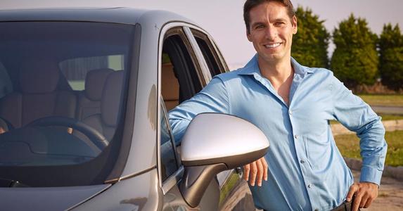 Car sharing: Make some money off your vehicle Smiling man standing next to grey vehicle | iStock.com/stockvisual