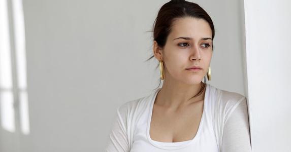 Solemn woman wearing white top, white walls background © iStock