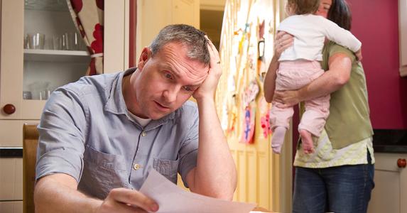 Stressed man reading documents in kitchen table with ...