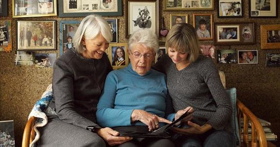 Three generations looking at photo album | LWA/Getty Images