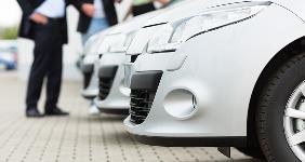 Two men and a woman standing in front of row of cars in car dealer lot Â© Kzenon/Shutterstock.com