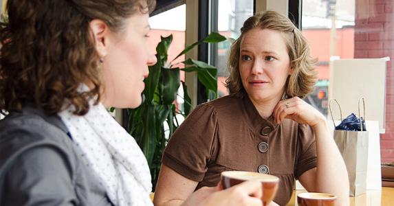 Two women chatting inside coffee shop © iStock