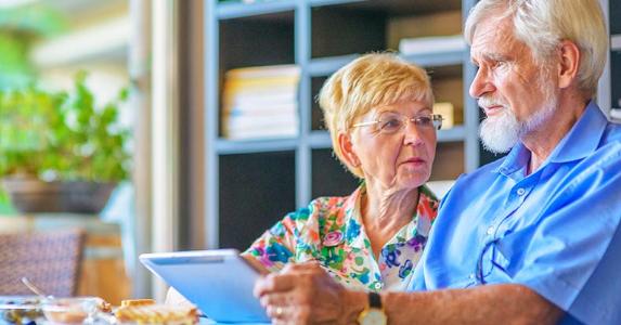 Can bank foreclose on reverse mortgage? Upset senior couple holding tablet receives bad news | iStock.com/Juergen Sack