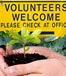 "Volunteers welcome" sign and hands holding a plant