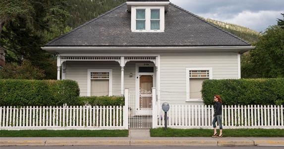 When's the best time to refi your mortgage? Woman walking by a house | John Elk III/Getty Images