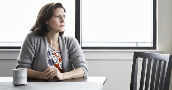 Sisters-in-law vie for man's life insurance Wife sitting alone at table | mother image/DigitalVision/Getty Images