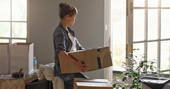 Can divorcing woman duck tax on vacation home sale? Serious woman carrying moving box | Gary Burchell/Getty Images