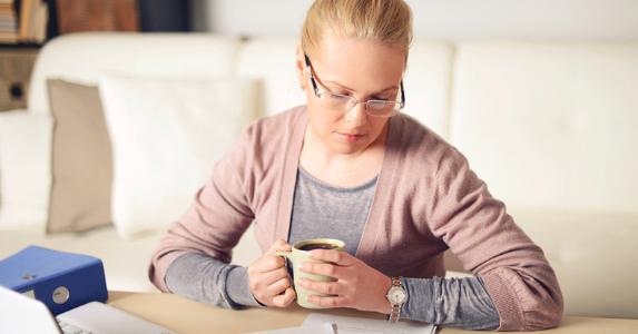 Woman working on paperwork in her living room © iStock