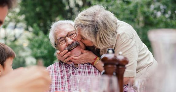 Social Security 'file and suspend' option to end Woman kissing husband's cheek at picnic table | Sofie Delauw/Cultura/Getty Images
